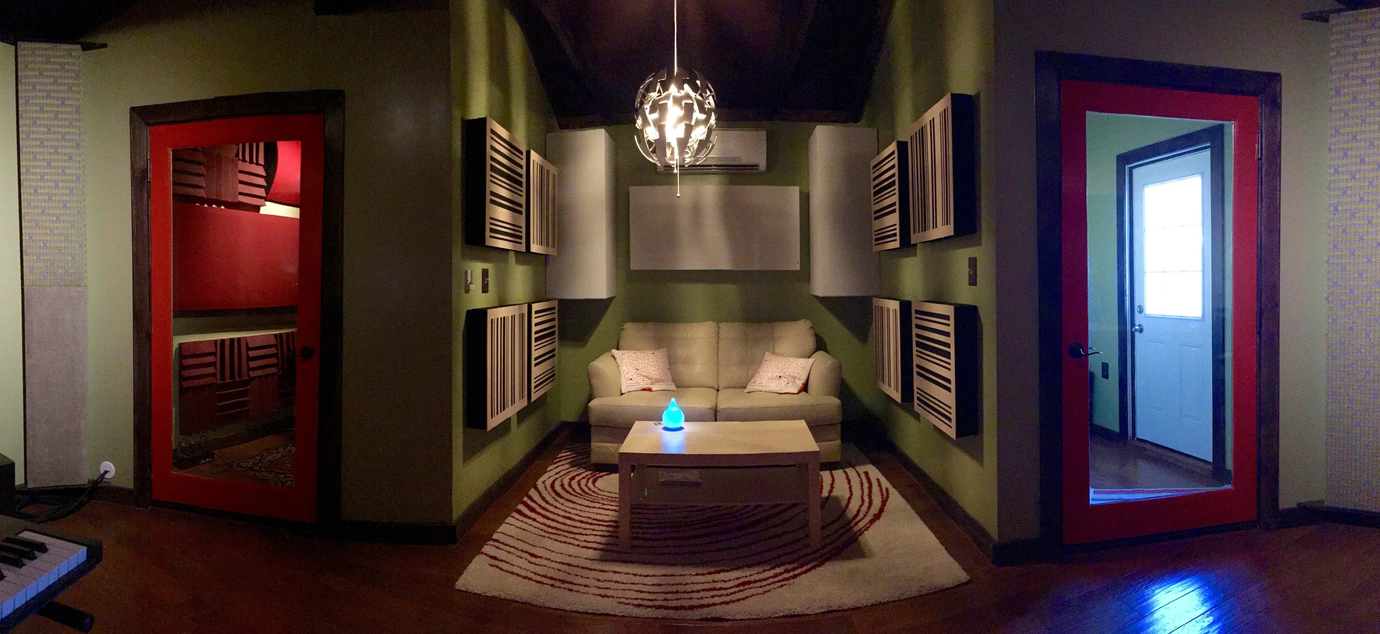 A panoramic view of the Bonzi Recording studio lounge, with GIK Acoustics GridFusor panels arranged symmetrically on the walls and a visible isolation booth through the red-framed doorway on the left