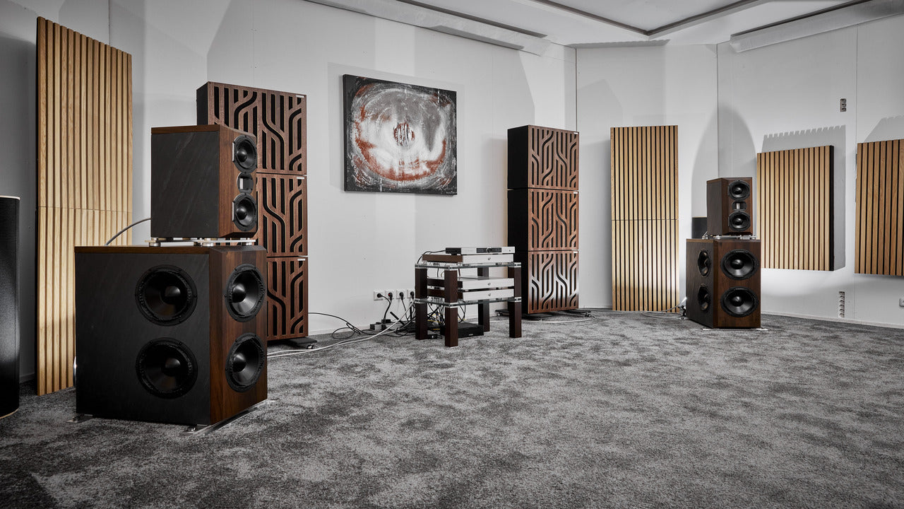 Hi-fi listening room featuring GIK Acoustics Amplitude™ Acoustic Panels in walnut and beech finishes alongside SlatFusor™ Acoustic Panels on the walls, with large floor-standing speakers and subwoofers positioned for two-channel listening.